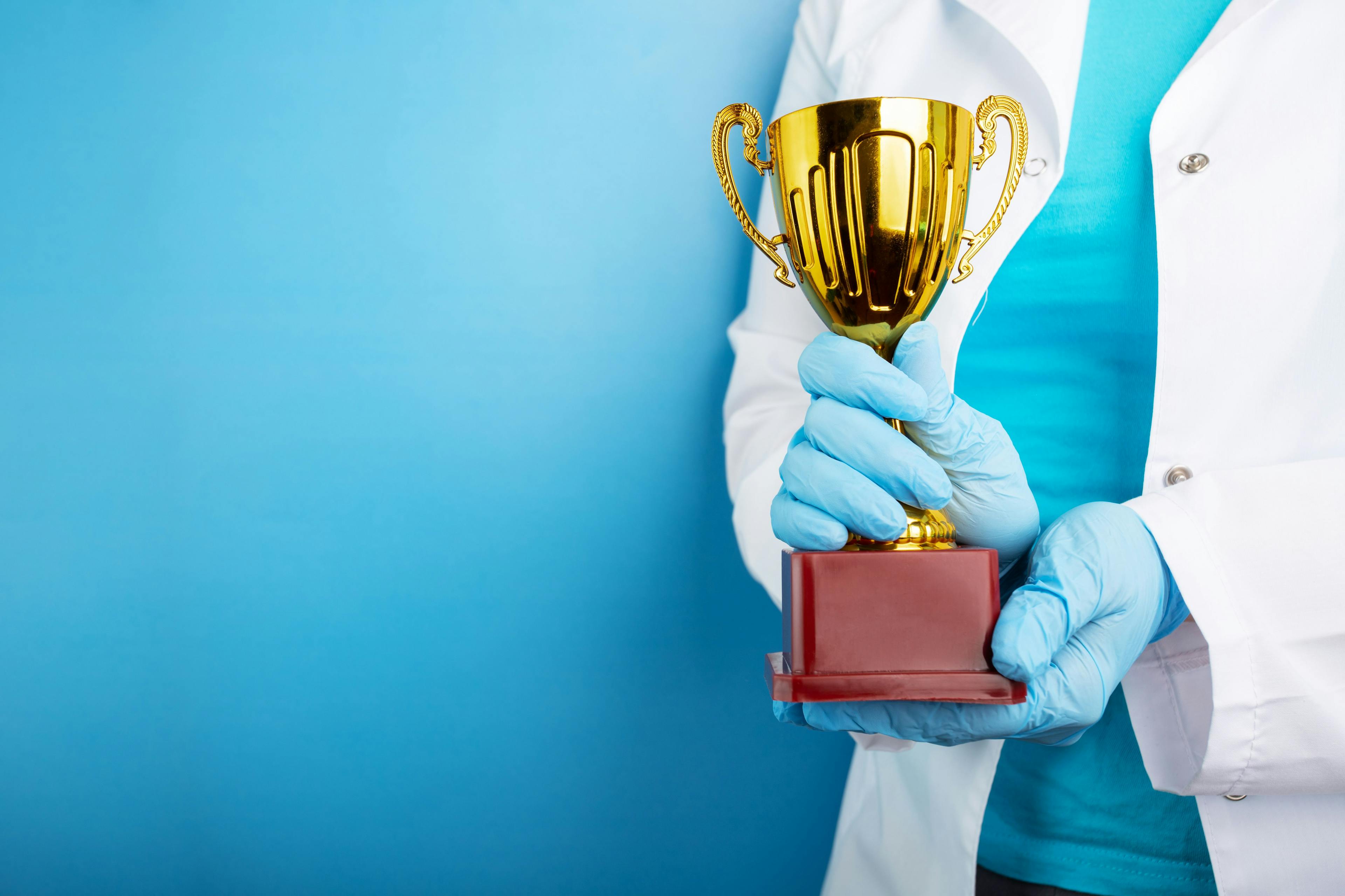 medical award, golden cup in doctor's hands, healthcare and medicine. Image Credit: Adobe Stock Images/yta